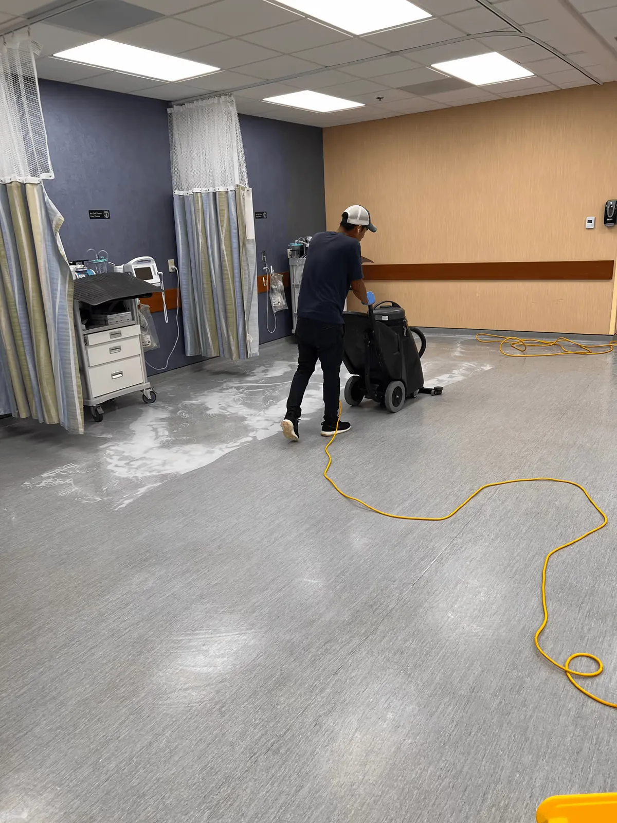 Cleaner running an auto scrubber on a medical office floor